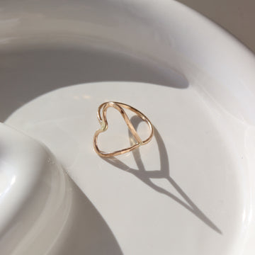 a hammered open heart shaped ring, photographed on a ceramic dish
