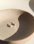 tiny gold filled circle studs handmade by Token Jewelry. Earrings are displayed on a jewelry dish.