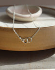 14k gold fill Lineage Necklace placed on a white jewelry dish. This necklace features jump rings representing parents, kids, and others you are able to pick the sizing of each jump ring.