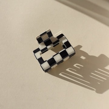 black and white checkered hair clip on a sunny tabletop