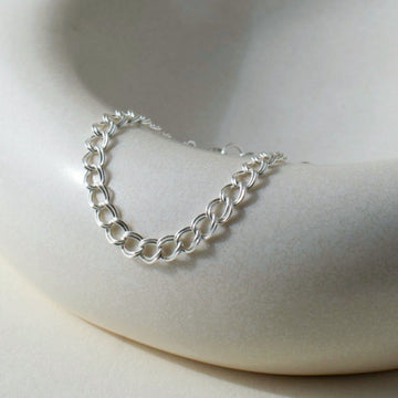 925 Sterling Silver Double link bracelet laid on top of a white clay plate. Jewelry is handmade in Eau Claire Wisconsin. Hypoallergenic jewelry made to live in.