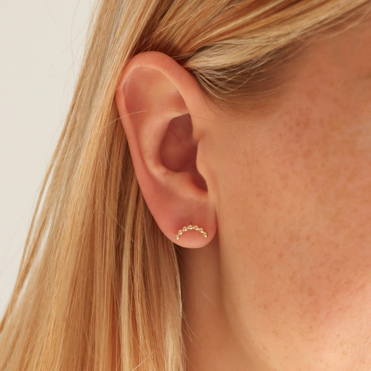 model wearing 14k gold fill sequin wire stud earrings on a light background