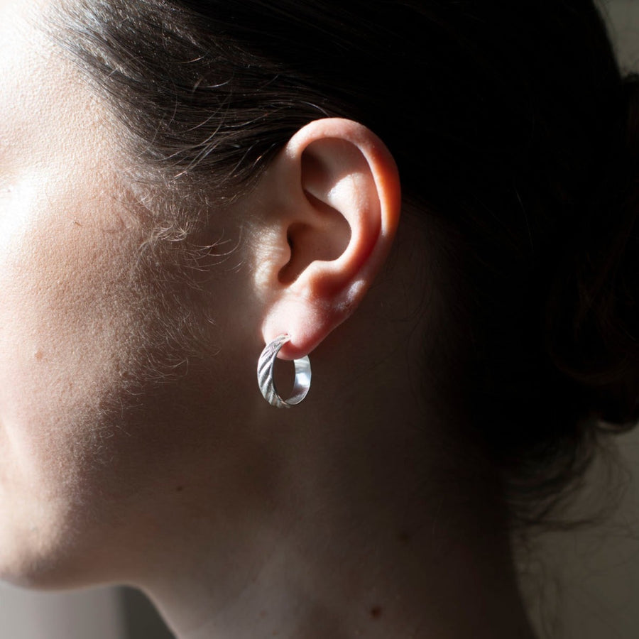 925 sterling silver 3/4" hoop earrings featuring a wave texture photographed on a brunette model