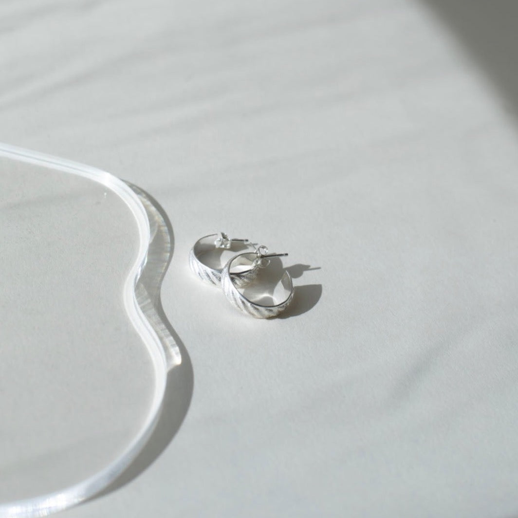 925 sterling silver 3/4&quot; hoop earrings featuring a wave texture photographed on a white tabletop