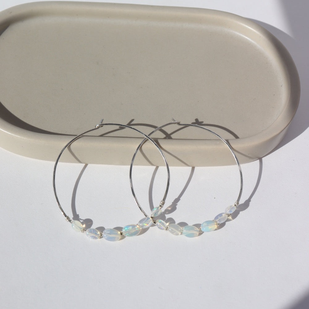 14k gold fill or sterling silver hoops, handmade and lightly hammered for shine, then adorned with six genuine australian opals that are delicately wire-wrapped. Handmade by Token Jewelry in Eau Claire, WI