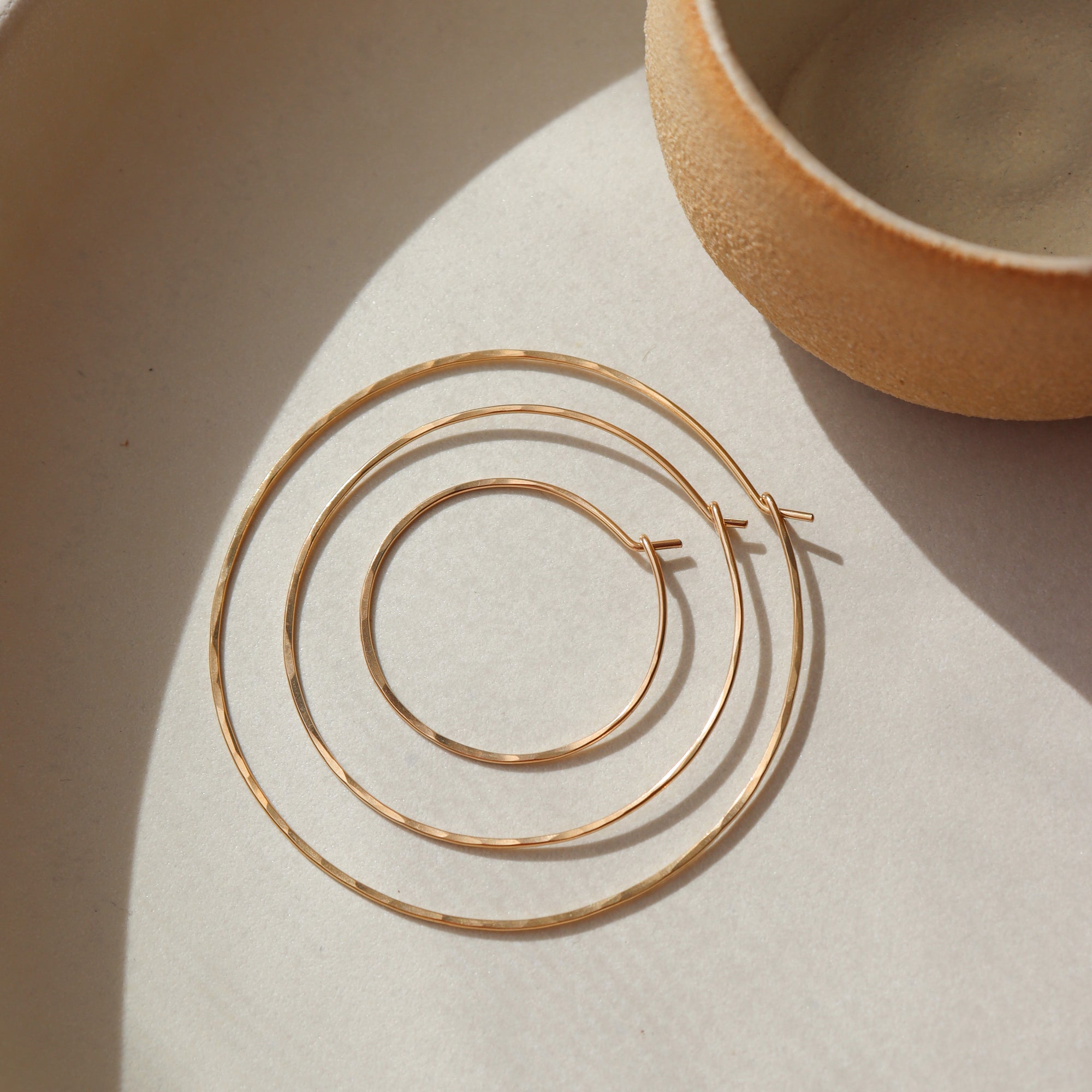 14k gold fill organic hoops placed in the sunlight 